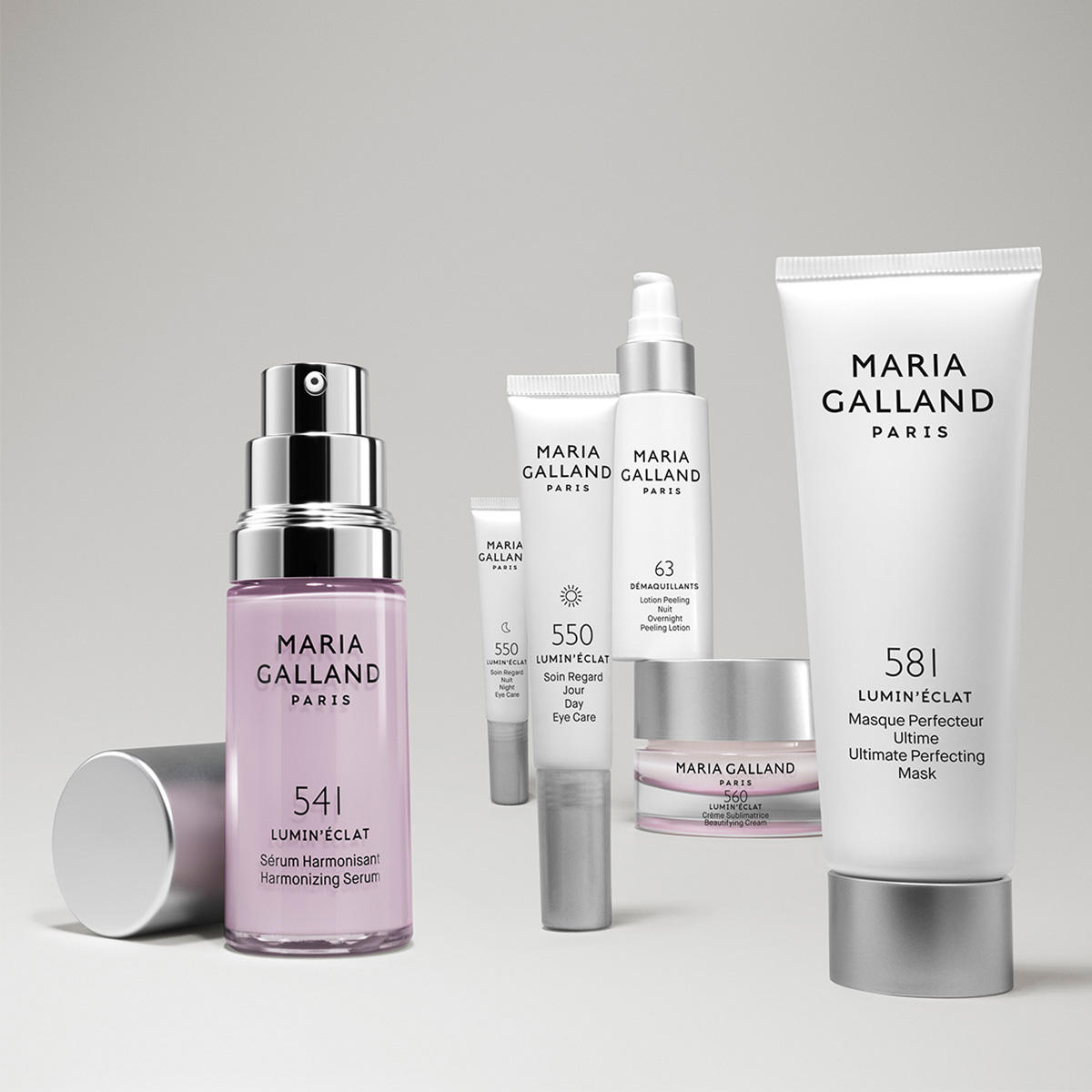 Eine Gruppe von Maria Galland Paris Hautpflegeprodukten, darunter Flaschen, Tuben und ein Tiegel, angeordnet auf einem hellgrauen Hintergrund. Die Artikel sind mit Nummern und Produktnamen beschriftet.