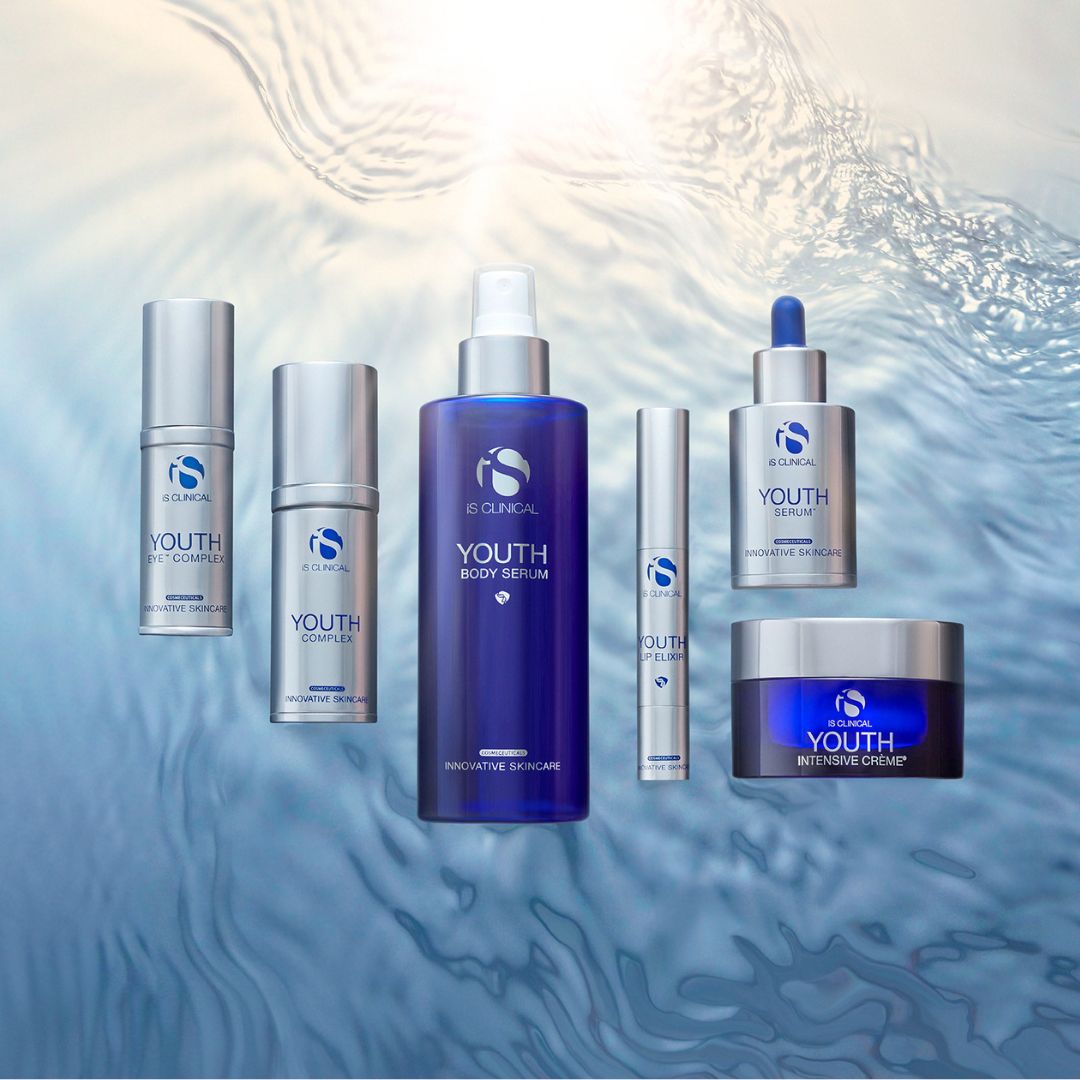Eine Reihe von iS Clinical Youth Hautpflegeprodukten in blauen und silbernen Verpackungen wird auf einem wasserähnlichen Hintergrund mit Lichtreflexen präsentiert.