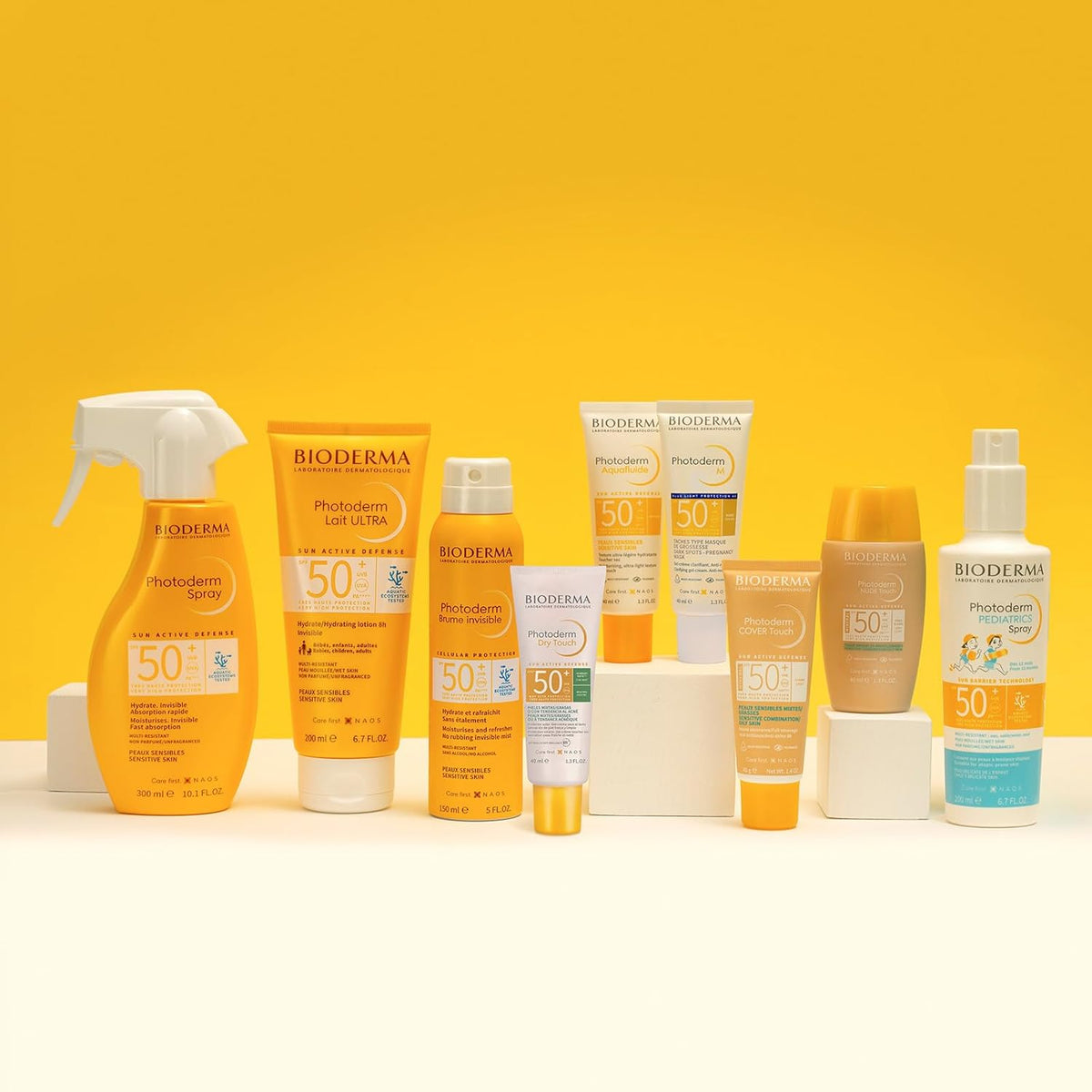 Eine Vielzahl von Bioderma-Sonnenschutzprodukten mit LSF 50 wird auf weißen Ständern vor einem leuchtend gelben Hintergrund präsentiert.