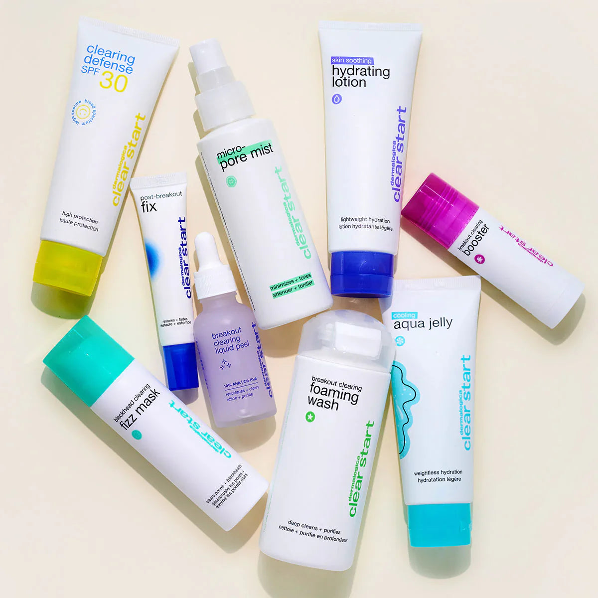 Eine flache Anordnung von neun Dermalogica Clear Start Hautpflegeprodukten, einschließlich Tuben, Flaschen und Spray, die auf einer hellbeigen Fläche angeordnet sind. Die Verpackung ist überwiegend weiß mit farbigen Akzenten.