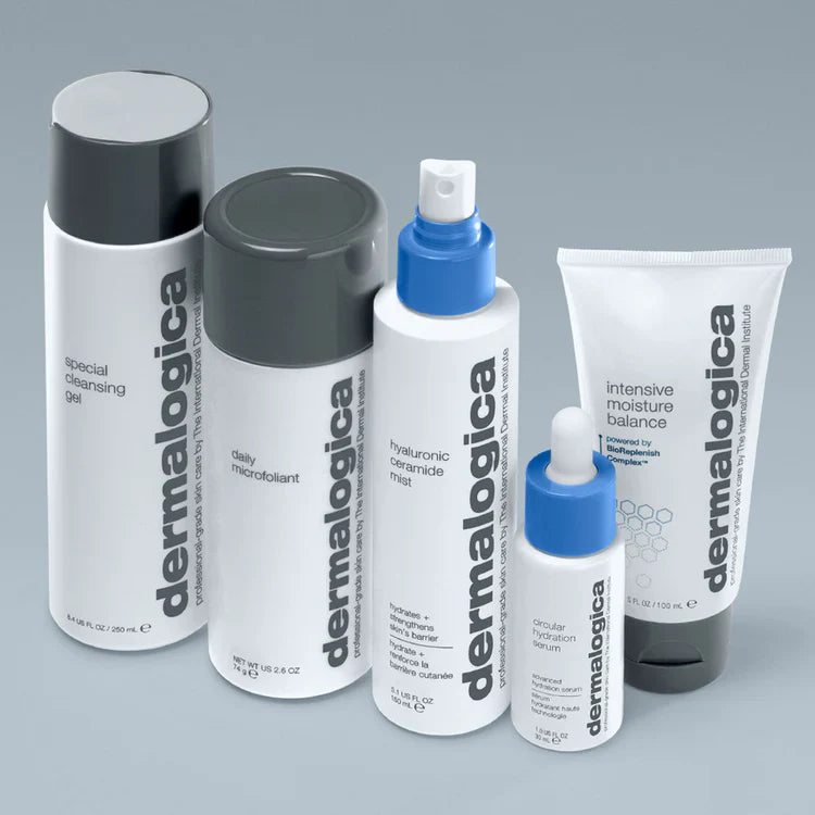 Fünf Dermalogica-Hautpflegeprodukte, darunter Reinigungsgel, Mikrofoliant, Ceramid-Nebel, Serum und Moisture Balance, sind aufrecht auf einer grauen Fläche mit minimalistischer weiß-grauer Verpackung angeordnet.