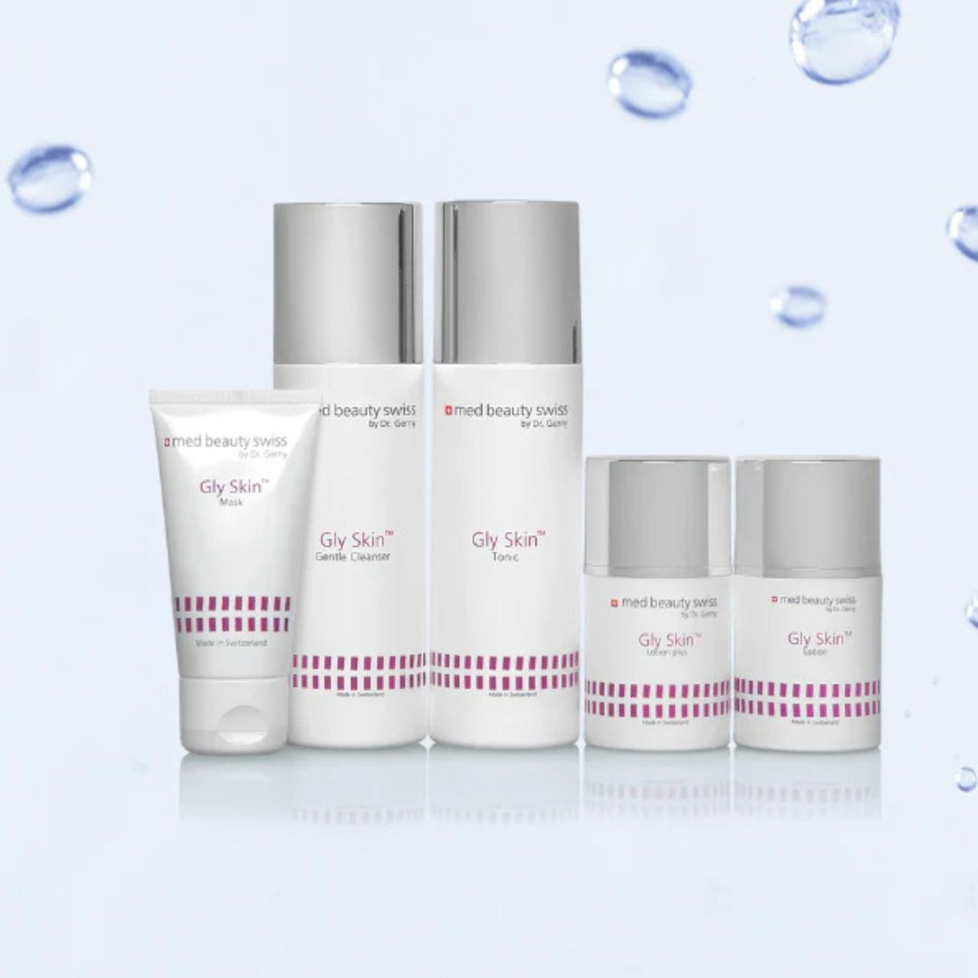 Sechs Med Beauty Swiss Gly Skin Hautpflegeprodukte sind auf einem hellblauen Hintergrund mit schwebenden Wassertropfen abgebildet. Die weißen Flaschen und Tuben haben silberne Verschlüsse und rote Beschriftungen.