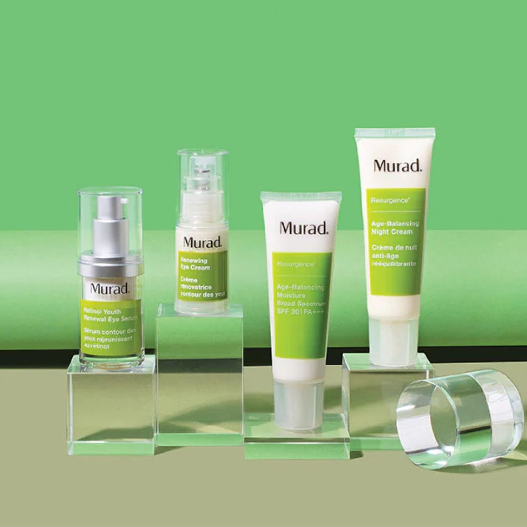 Vier Murad-Hautpflegeprodukte mit grüner und weißer Verpackung werden auf klaren Acrylständern vor einem grünen Hintergrund präsentiert. Zu den Produkten gehören Cremes und Seren aus der Resurgence-Linie.