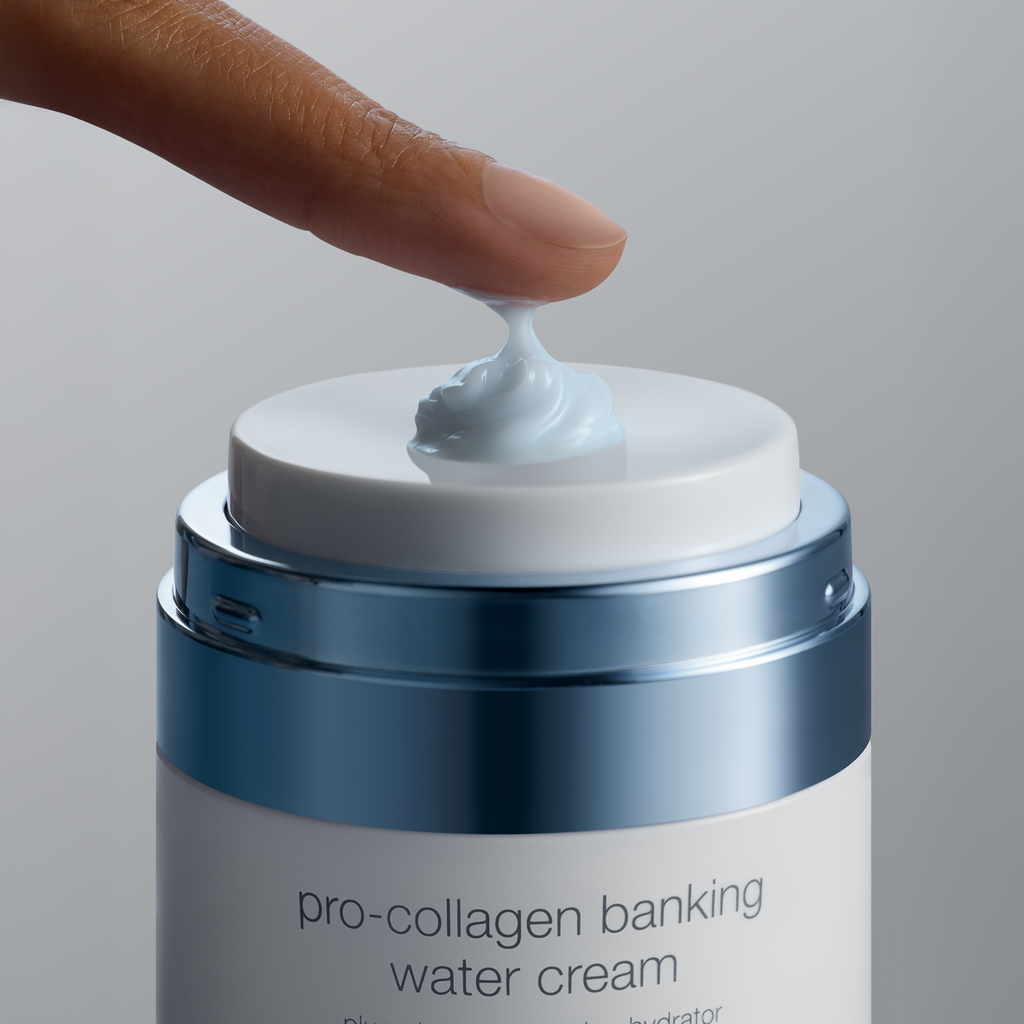 Eine Nahaufnahme zeigt einen Finger, der auf die Pumpe eines blau-weißen dermalogica Pro-Collagen Banking Cream Tiegels drückt und einen kleinen Klecks hellblauer Creme ausgibt.