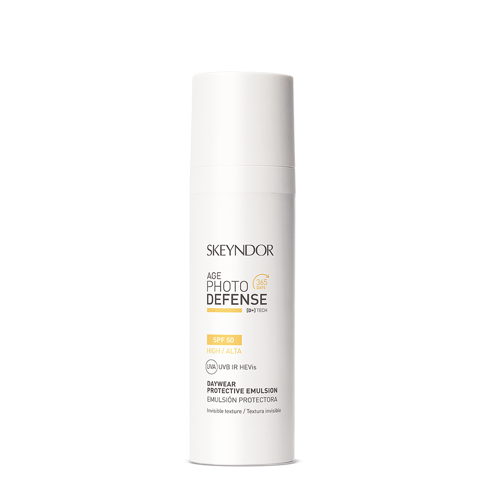 Eine weiße Flasche Skeyndor AGE PHOTO DEFENSE DAYWEAR PROTECTIVE EMULSION SPF50 mit Pumpspender und schwarzer und goldener Schrift. Bietet hohen Schutz mit UVA-, UVB- und HEVis-Filtern.