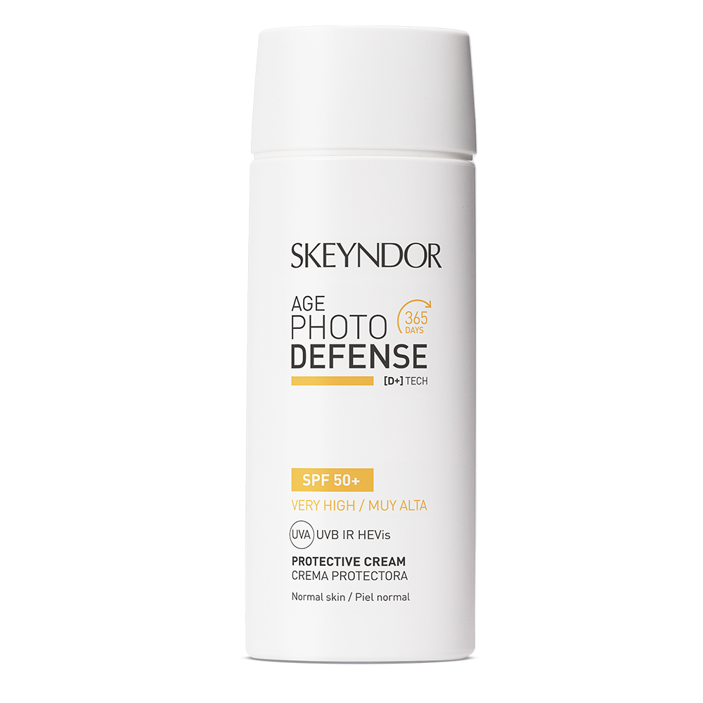 Eine weiße Flasche Skeyndor AGE PHOTO DEFENSE PROTECTIVE CREAM SPF50+ für normale Haut, mit schwarzer und gelber Schrift, einer zylindrischen Kappe und einem Etikett, das den UVA-, UVB- und IR-Schutz hervorhebt.