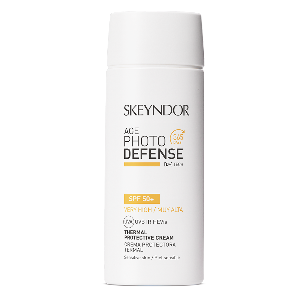 Eine weiße Flasche Skeyndor AGE PHOTO DEFENSE THERMAL PROTECTIVE CREMA SPF50+ für empfindliche Haut. Auf dem Etikett stehen in schwarzer und gelber Schrift der Markenname und Angaben zum hohen Sonnenschutz und zur täglichen Anwendung.