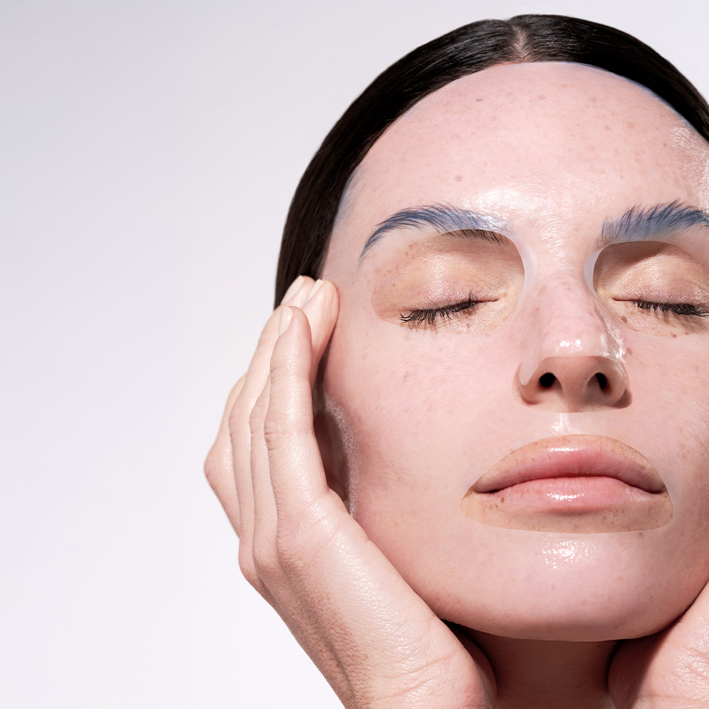 Nahaufnahme einer Person mit geschlossenen Augen, die LPG - Post Care Collagen Mask von LPG unter den Augen und auf den Lippen trägt und mit einer Hand sanft ihr Gesicht berührt, vor einem hellen Hintergrund.