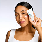 Eine Frau mit einem Klecks Creme auf der Wange hält eine Tube NeoStrata Restore – PHA Barrier Recovery Cream für empfindliche Haut in der Hand.