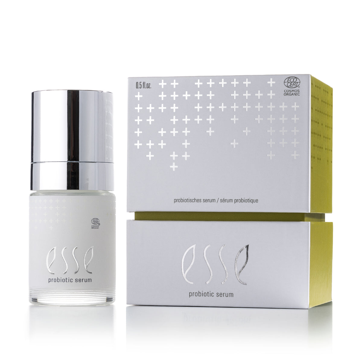 Eine Glasflasche mit Pumpverschluss des ESSE R10 PLUS Probiotic Serums neben der dazugehörigen quadratischen Verpackung; beide sind mit silbernen Pluszeichen und dem Markenlogo versehen.