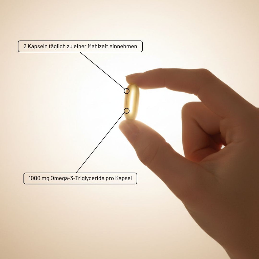 Eine Hand hält eine goldene Medigevity – Medi Omega-3-Gelkapsel, auf der die Einnahmeempfehlung steht, täglich zwei Kapseln zu einer Mahlzeit einzunehmen, und dass jede Kapsel 1000 mg Omega-3-Triglyceride enthält.