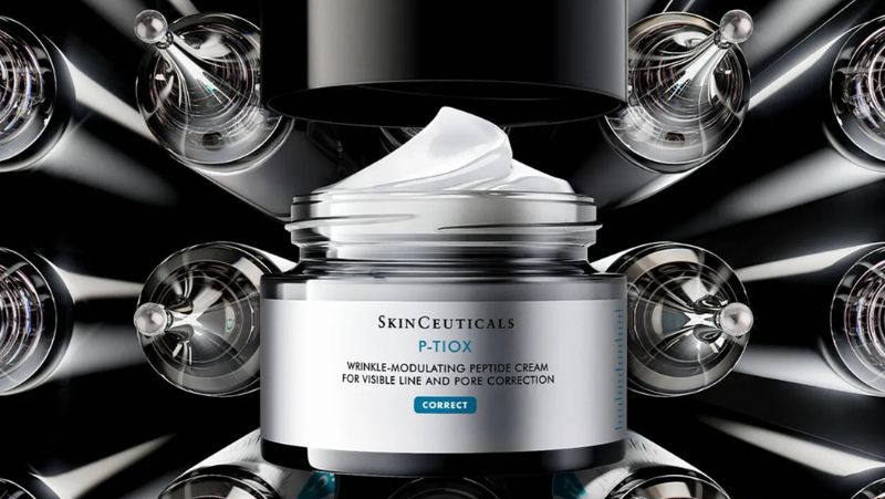Ein Tiegel der SkinCeuticals P-TIOX Peptidcreme zur Faltenmodulation mit abgenommenem Deckel, umgeben von einem metallischen, geometrischen Hintergrund.
