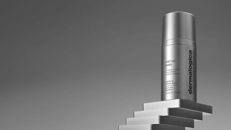 Eine Flasche mit dem Dermalogica Smart Eye Density-Serum steht auf einem Stapel grauer quadratischer Podeste.
